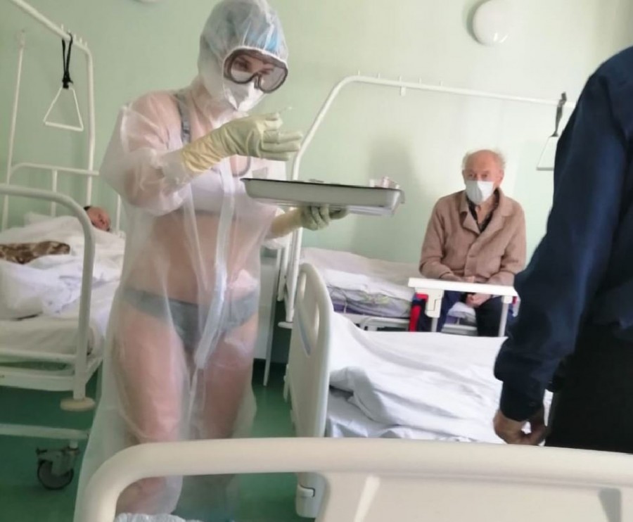 Așa să tot ai COVID: asistentă medicală fotografiată în timp ce îngrijeşte bolnavii în costum de protecţie transparent, îmbrăcat deasupra lenjeriei intime